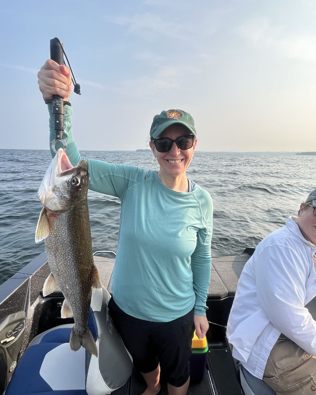 Smiling angler holding a Lake Champlain lake trout on a Vermont fishing charter