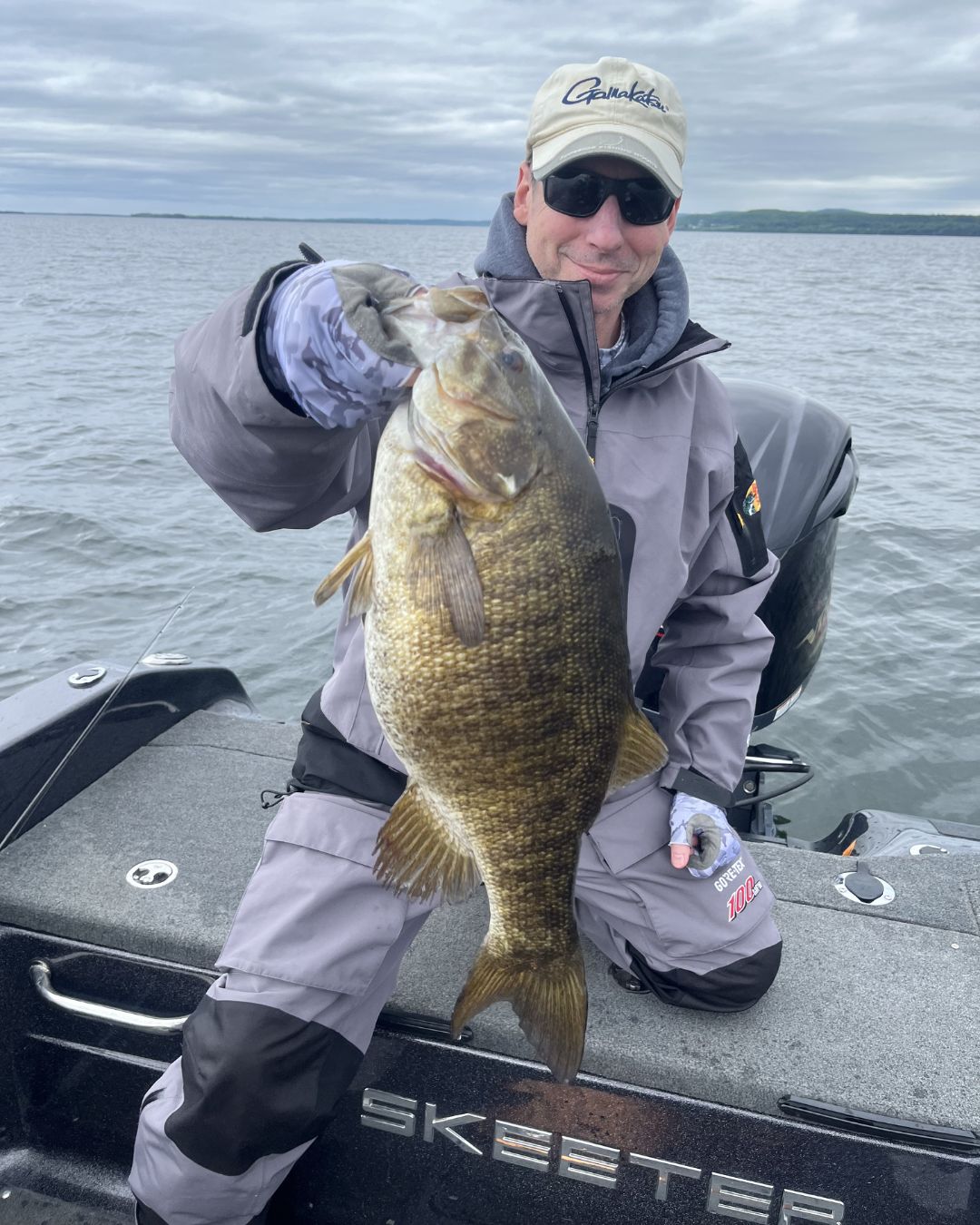 Angler holding a large Vermont bass on a Lake Champlain fishing charter